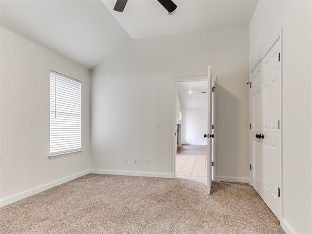 unfurnished room featuring a ceiling fan, light colored carpet, vaulted ceiling, and baseboards