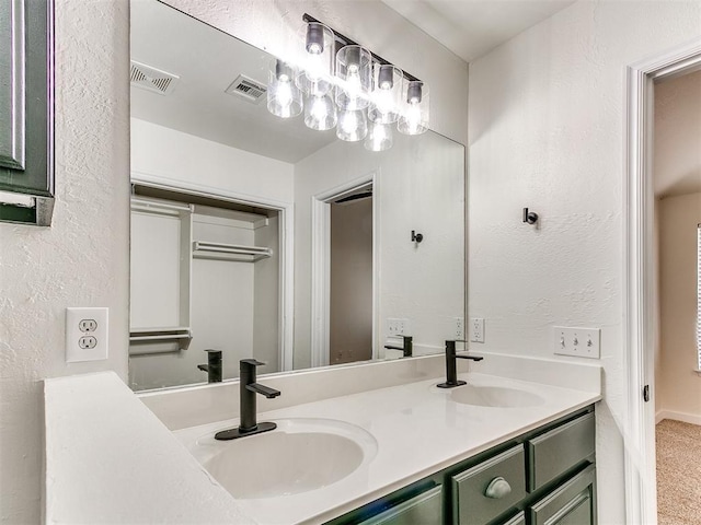 full bath with a textured wall, visible vents, and a sink