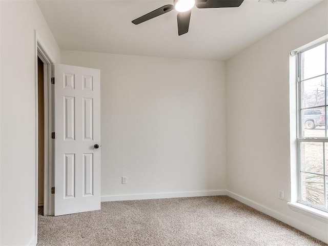 spare room featuring a wealth of natural light, light carpet, ceiling fan, and baseboards