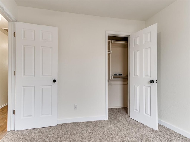 unfurnished bedroom with carpet floors, baseboards, and a closet