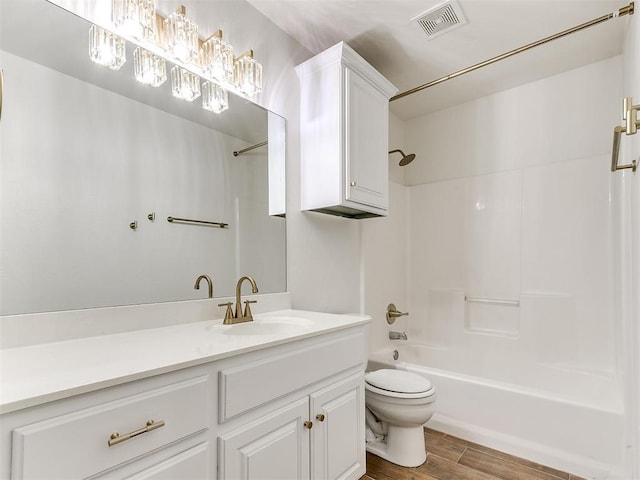 full bathroom with toilet, wood finished floors, vanity, visible vents, and washtub / shower combination