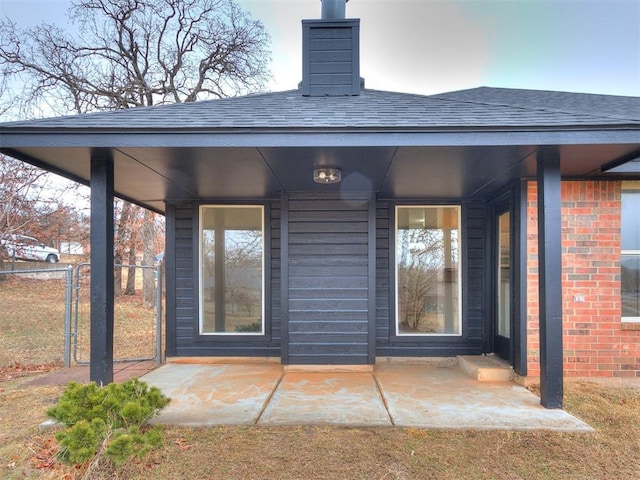 back of house featuring roof with shingles, fence, and brick siding