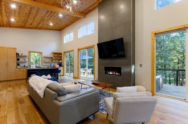 639 Woodland Hills Trl, Broken Bow, OK 74728 - living room with a tile fireplace, a wealth of natural light, light wood-type flooring, wooden ceiling, and beam ceiling