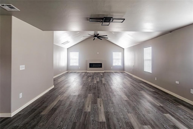 unfurnished living room featuring a wealth of natural light, dark hardwood / wood-style floors, ceiling fan, and vaulted ceiling