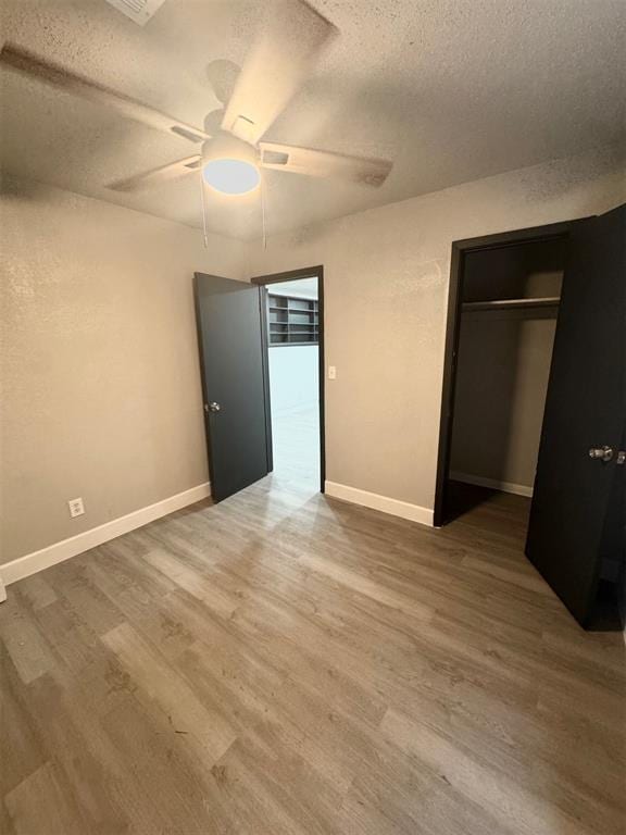 unfurnished bedroom with ceiling fan, wood-type flooring, a closet, and a textured ceiling