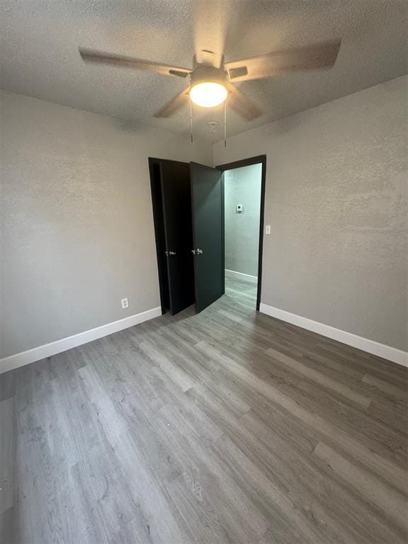 spare room with ceiling fan, wood-type flooring, and a textured ceiling