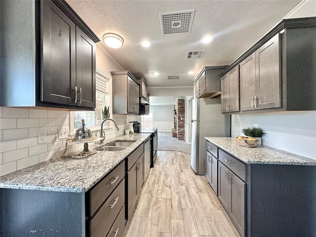 kitchen featuring light stone counters, black range with electric stovetop, light hardwood / wood-style flooring, and sink