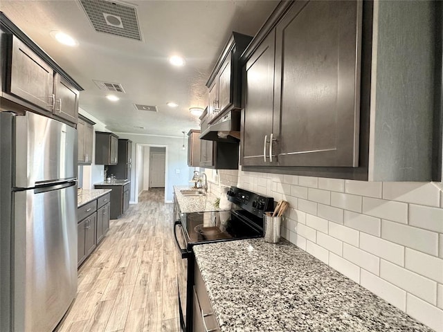 kitchen with light hardwood / wood-style flooring, stainless steel refrigerator, light stone counters, dark brown cabinetry, and black / electric stove