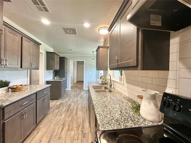 kitchen with sink, dark brown cabinets, black / electric stove, light stone countertops, and exhaust hood