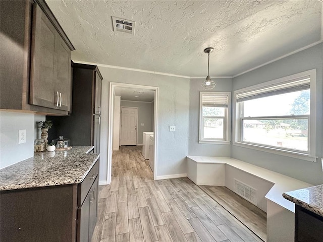 kitchen featuring stone counters, dark brown cabinets, ornamental molding, light hardwood / wood-style floors, and decorative light fixtures