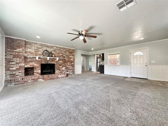 unfurnished living room featuring ceiling fan, a fireplace, a textured ceiling, and carpet flooring