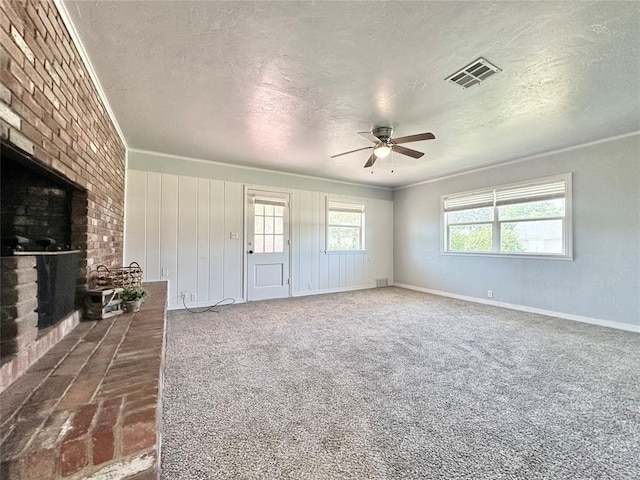 unfurnished living room with ceiling fan, a brick fireplace, dark carpet, and a textured ceiling