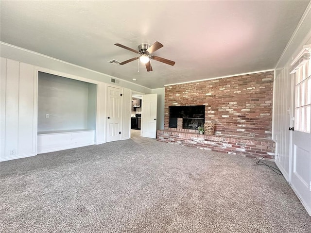 unfurnished living room with ceiling fan, brick wall, a brick fireplace, and carpet