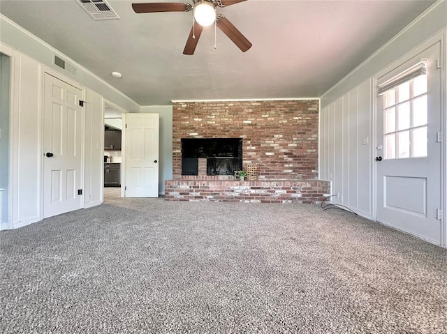 unfurnished living room with a brick fireplace, ornamental molding, and carpet flooring