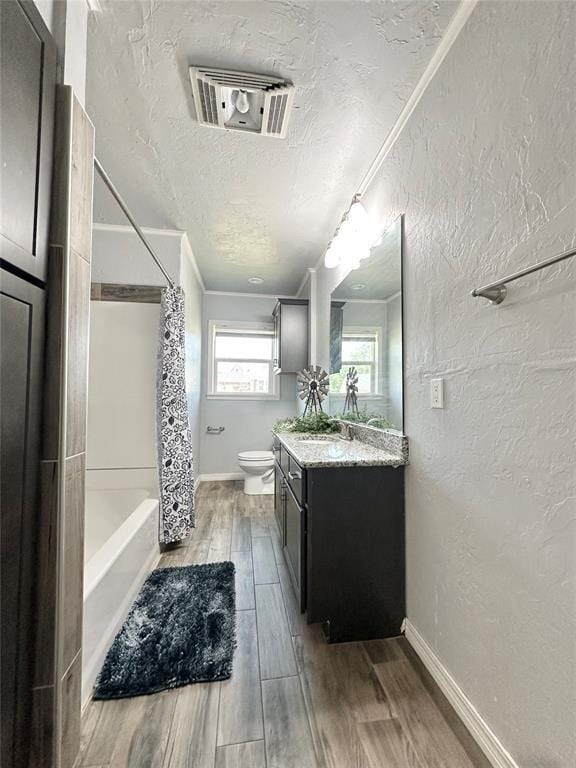 full bathroom featuring toilet, crown molding, a textured ceiling, vanity, and shower / bath combo with shower curtain