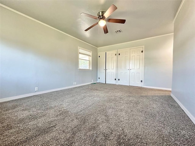 unfurnished bedroom featuring crown molding, carpet, two closets, and ceiling fan