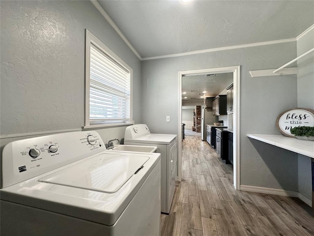 washroom with independent washer and dryer, ornamental molding, and light hardwood / wood-style flooring