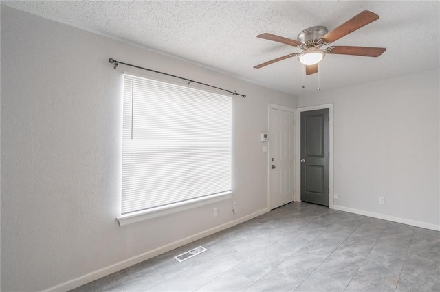 empty room with ceiling fan and a textured ceiling