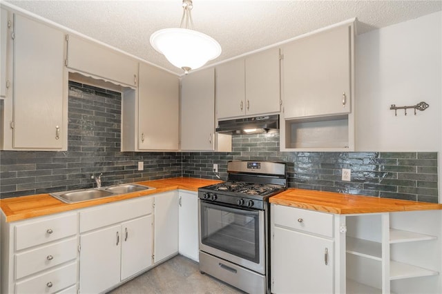 kitchen featuring butcher block countertops, sink, white cabinetry, stainless steel gas range oven, and decorative light fixtures