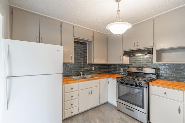 kitchen featuring white fridge, butcher block counters, sink, and stainless steel gas range