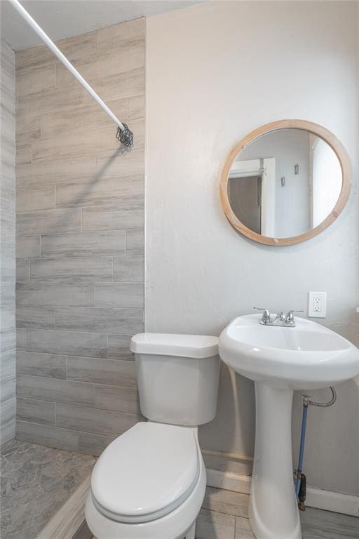 bathroom with toilet and a tile shower