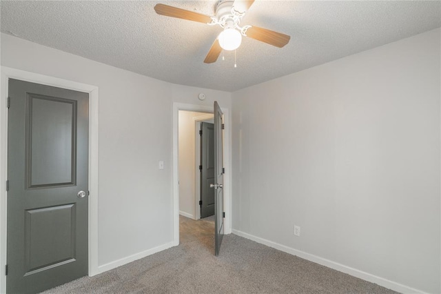 unfurnished bedroom featuring light carpet, ceiling fan, and a textured ceiling