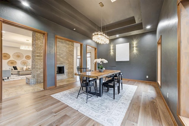 10401 Fawn Trace Rd, Mustang, OK 73064 - dining room featuring an inviting chandelier, a tray ceiling, wood finished floors, baseboards, and a fireplace