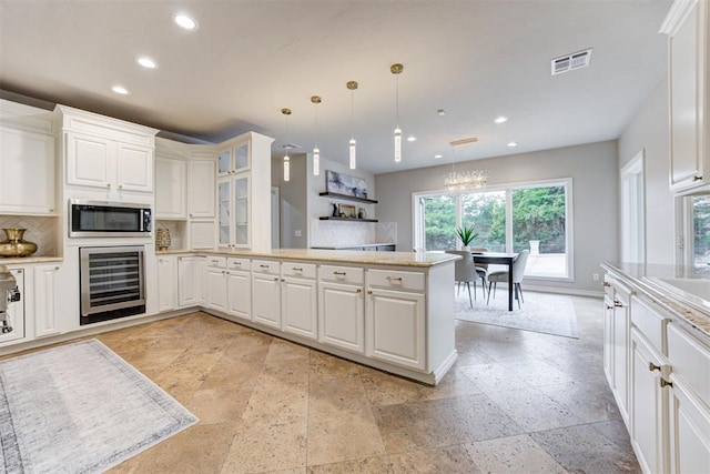 10401 Fawn Trace Rd, Mustang, OK 73064 - kitchen featuring a peninsula, stainless steel microwave, visible vents, recessed lighting, and beverage cooler