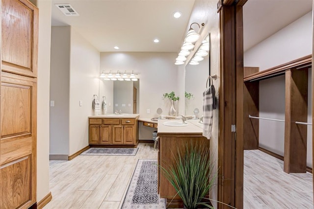 10401 Fawn Trace Rd, Mustang, OK 73064 - bathroom with wood finished floors, two vanities, visible vents, and a sink