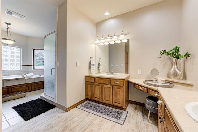 10401 Fawn Trace Rd, Mustang, OK 73064 - full bathroom featuring a bath, two vanities, a sink, visible vents, and wood finished floors