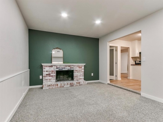 unfurnished living room featuring a fireplace and light colored carpet