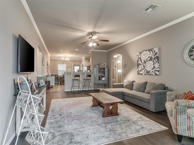 living room with dark hardwood / wood-style flooring, ceiling fan with notable chandelier, and crown molding