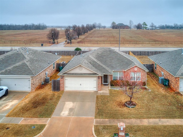 view of front of property featuring cooling unit, a garage, a front lawn, and a rural view