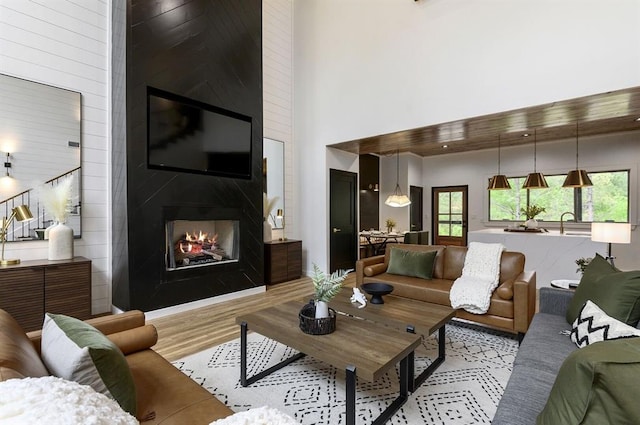 living room featuring a high ceiling, a large fireplace, and light hardwood / wood-style flooring