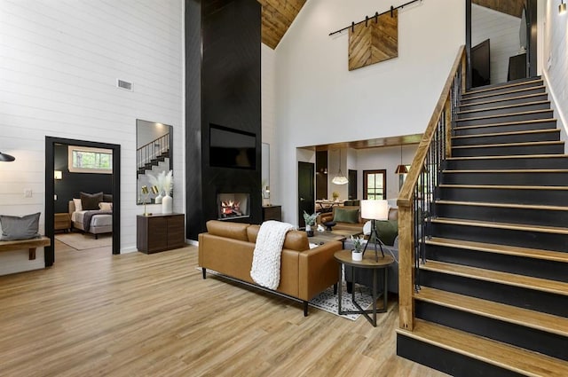 living room with a fireplace, high vaulted ceiling, and light hardwood / wood-style flooring