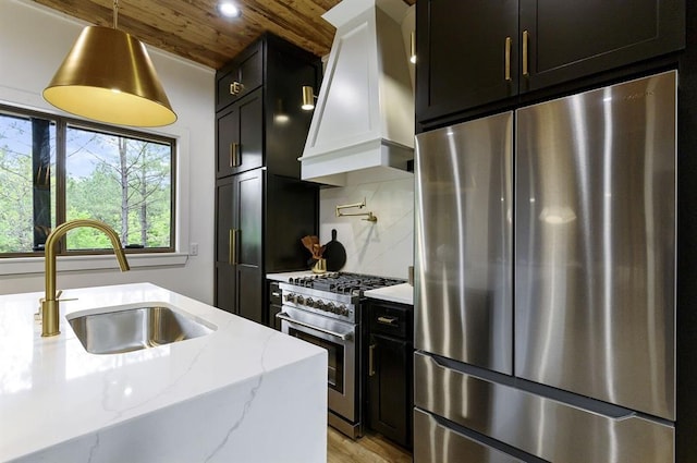 kitchen featuring sink, custom exhaust hood, light stone counters, tasteful backsplash, and stainless steel appliances