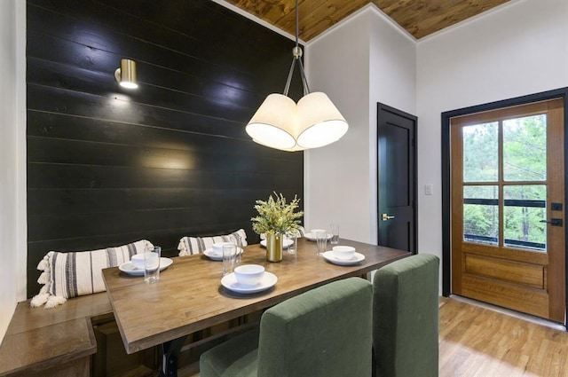 dining room with hardwood / wood-style flooring, wood ceiling, and wood walls