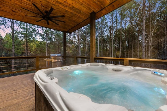 deck at dusk with a hot tub, area for grilling, and ceiling fan