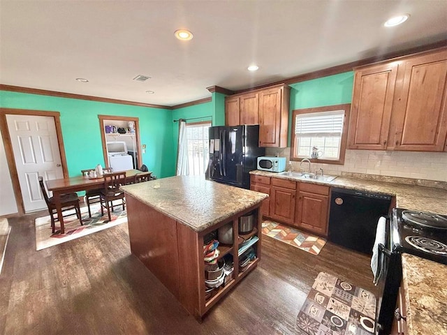 kitchen featuring black appliances, dark wood-type flooring, plenty of natural light, and a sink