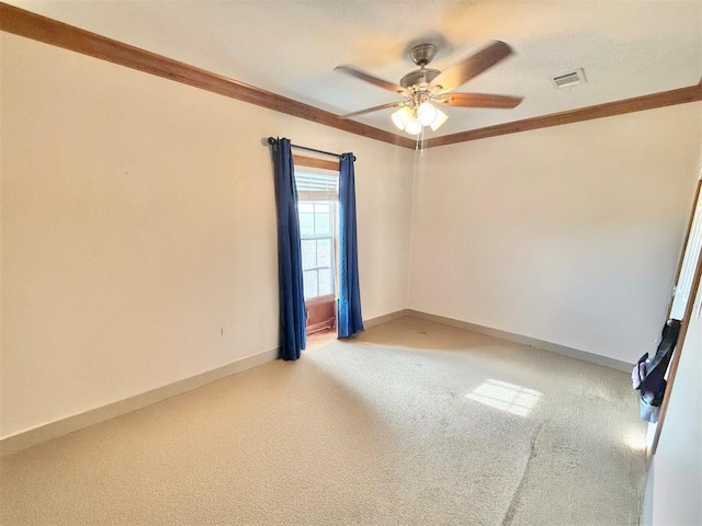 spare room featuring crown molding, visible vents, a ceiling fan, light carpet, and baseboards