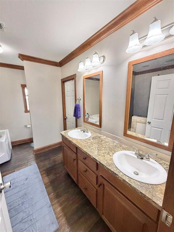 bathroom featuring crown molding, a sink, and wood finished floors