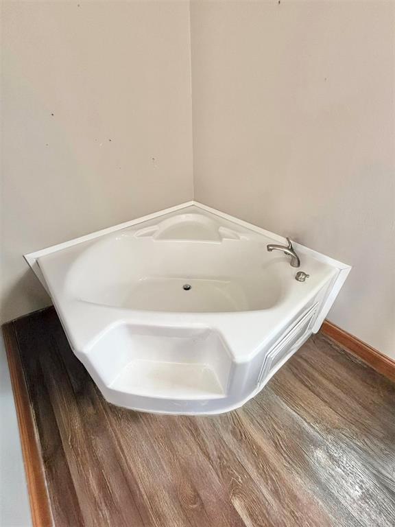 full bathroom featuring a garden tub, baseboards, and wood finished floors