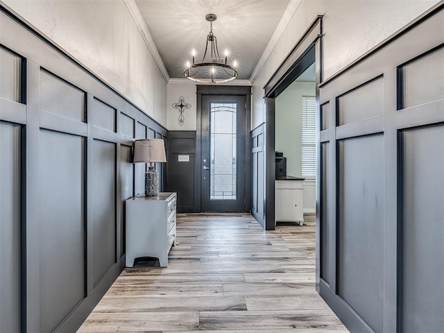 foyer featuring crown molding, a chandelier, and light hardwood / wood-style floors