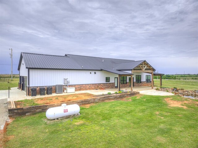 1632 County Road 1250, Tuttle, OK 73089 - view of front facade featuring central AC, metal roof, a front lawn, a patio area, and board and batten siding