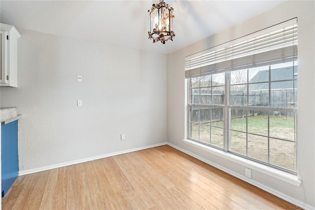 unfurnished dining area featuring a notable chandelier and light wood-type flooring