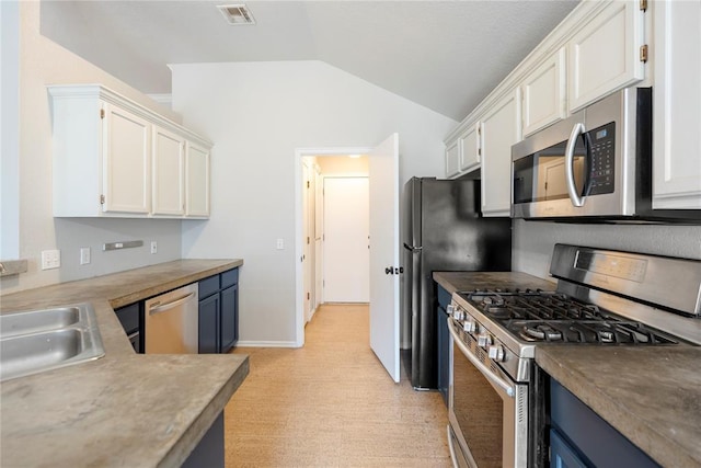 kitchen with blue cabinets, white cabinetry, appliances with stainless steel finishes, and lofted ceiling