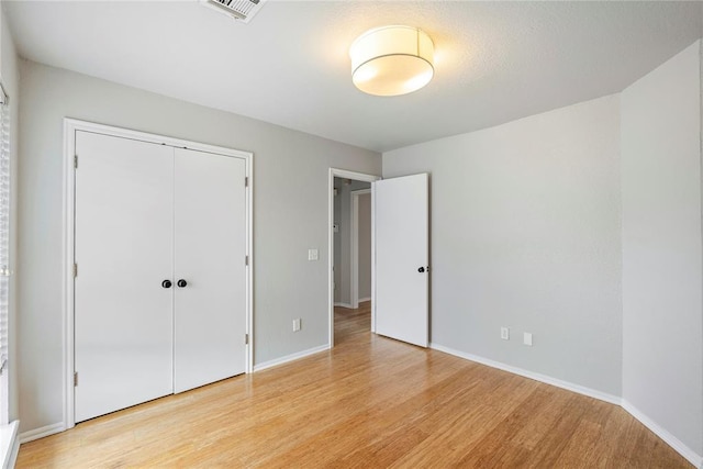 unfurnished bedroom with a closet and light wood-type flooring