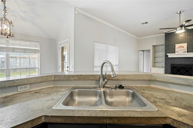 kitchen with ornamental molding, lofted ceiling, sink, and a fireplace