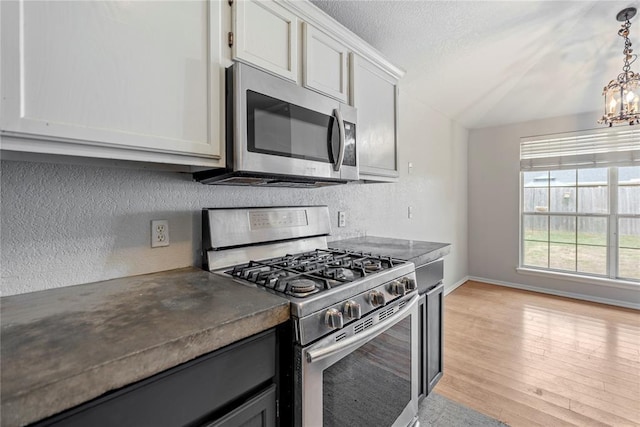 kitchen with white cabinetry, a chandelier, a textured ceiling, light wood-type flooring, and stainless steel appliances