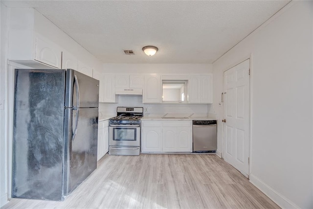 kitchen featuring white cabinetry, light wood-type flooring, a textured ceiling, and appliances with stainless steel finishes